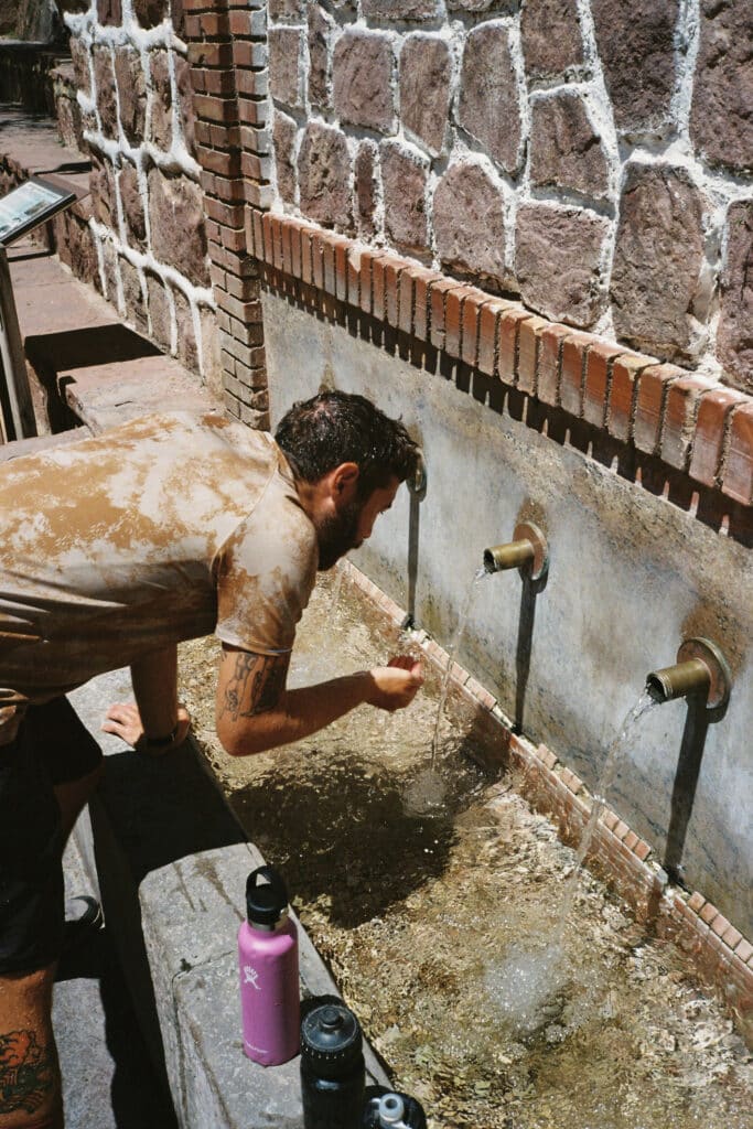 Ciclista llenando bidones de agua en una fuente durante el Camí dels Assagadors